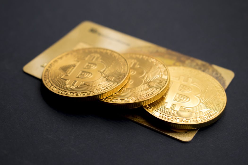 монетки биткйона btc лежат на золотой пластиковой карточке