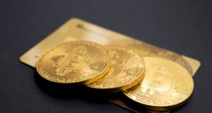 монетки биткйона btc лежат на золотой пластиковой карточке