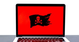 фотография MacBook с красным экраном и изображением пиратского флага