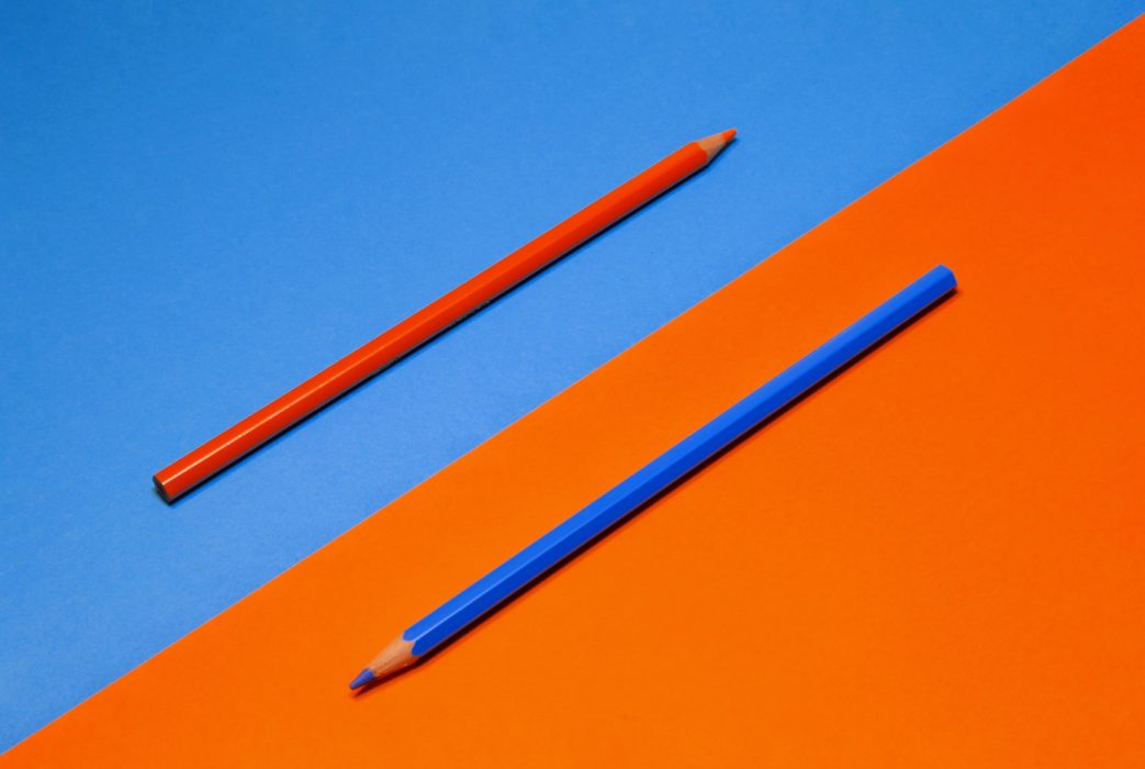 два разноцветных карандаша лежат на разных фонах